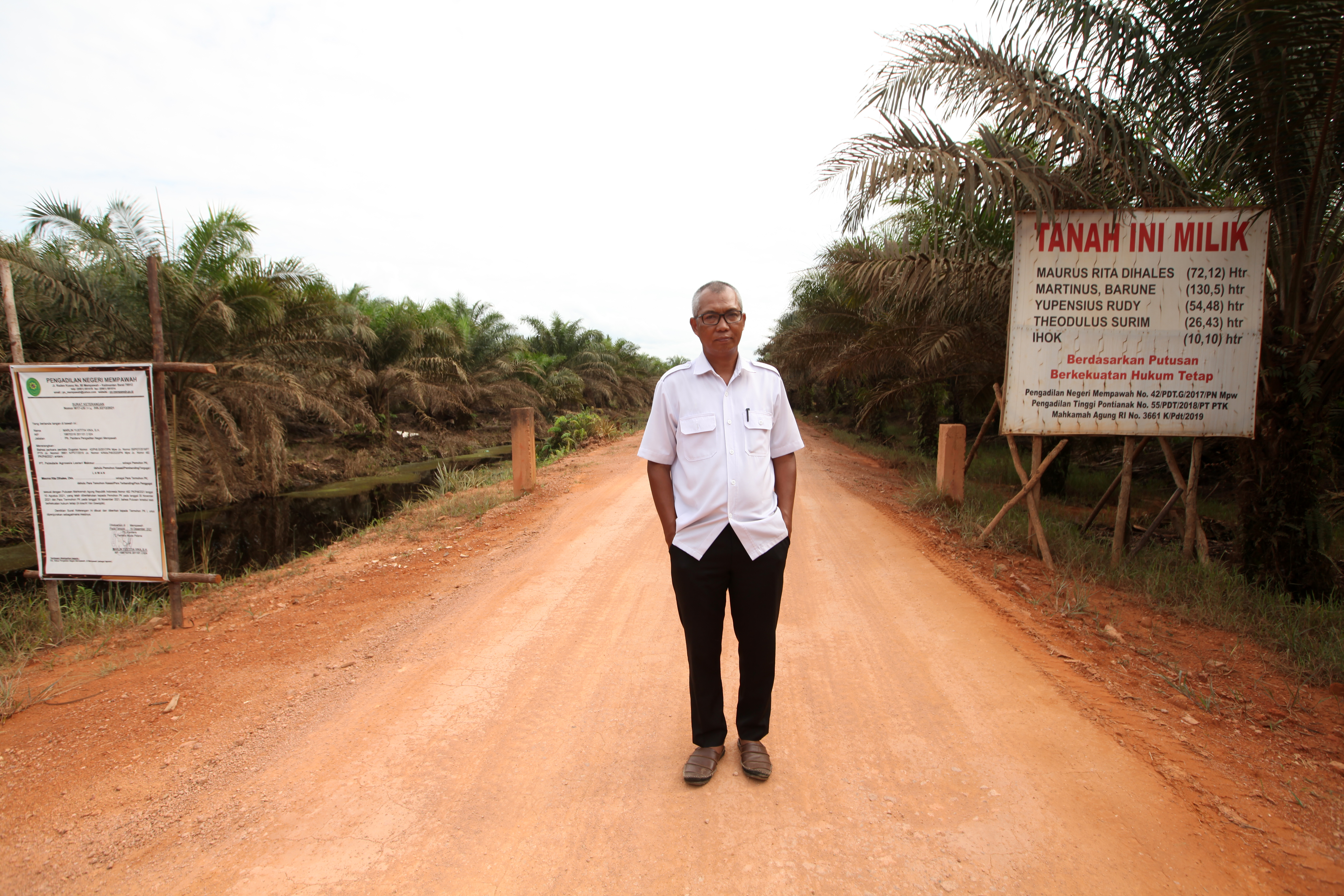 Rita stands on the land that he transferred to PT Palmdale in 2010. The signs display the Supreme Court’s judgement and the words “This is our land”. Photo: Saga Chang.